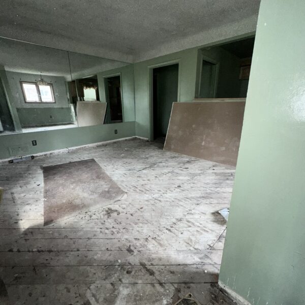 An empty room with wood floors and a mirror.