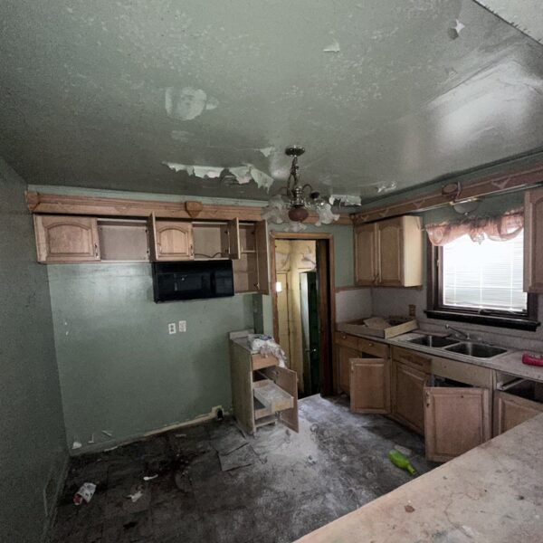 An empty kitchen with a sink and counter tops.