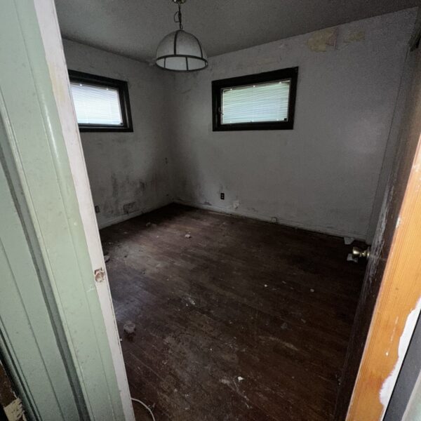 An empty room with wood floors and a window.