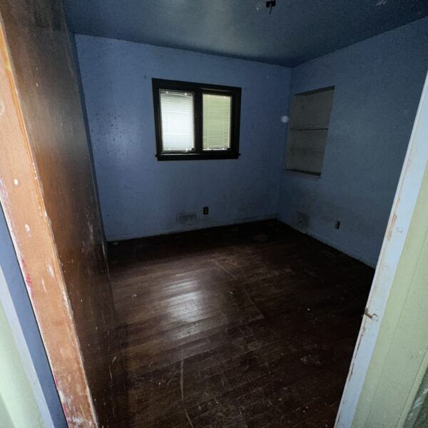 An empty room with wood floors and a window.