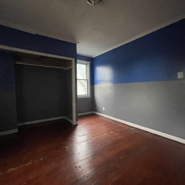 An empty room with blue walls and hardwood floors.