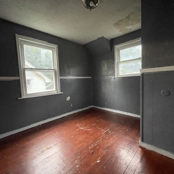 An empty room with gray walls and wood floors.