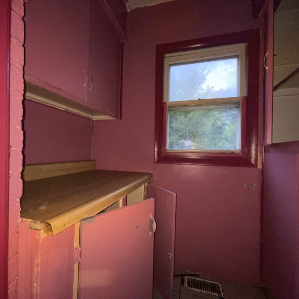 A kitchen with pink cabinets and a window.
